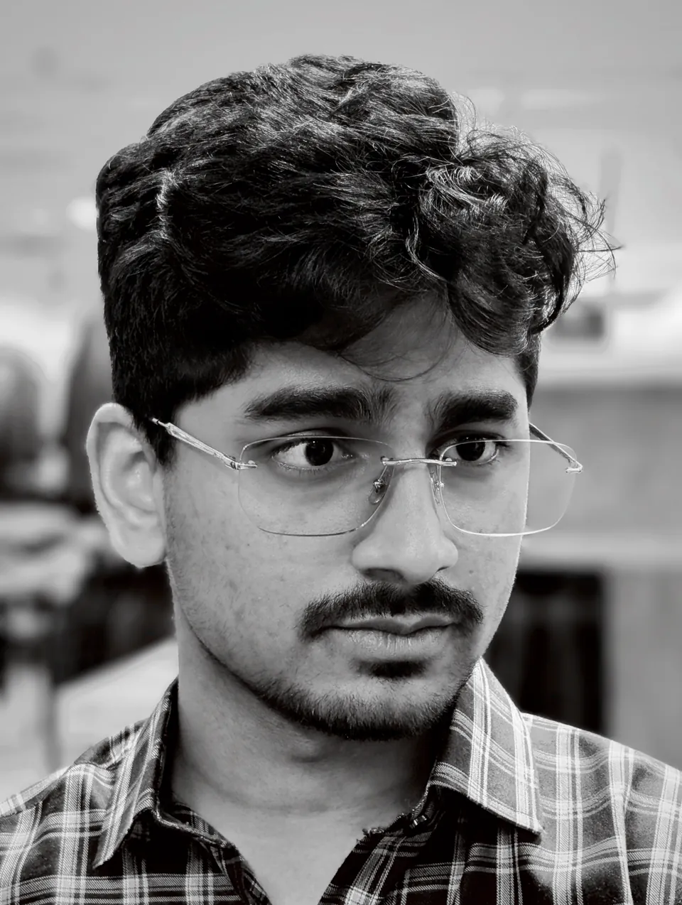 Kenny Patel in glasses and a checked shirt, looking off to one side.